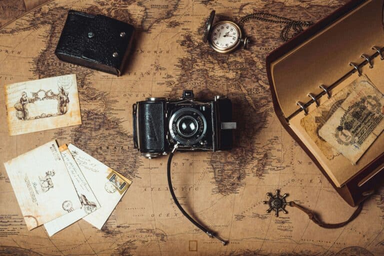 Storytelling territoriale. Una mappa cartacea aperta su un tavolo di legno con una bussola e una macchina fotografica vintage.